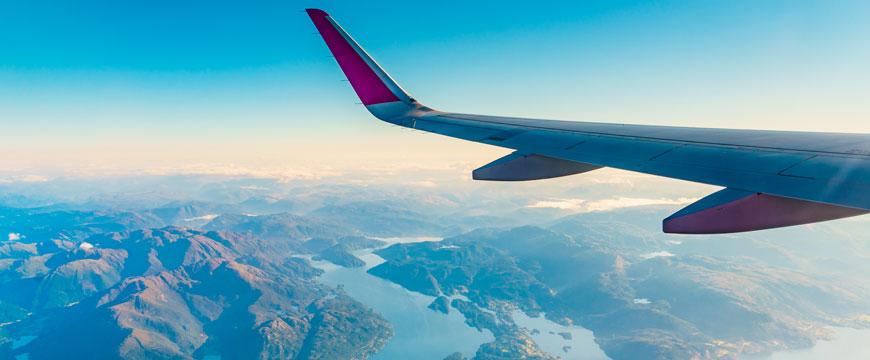 Airplane Wing in the Sky Over Mountains