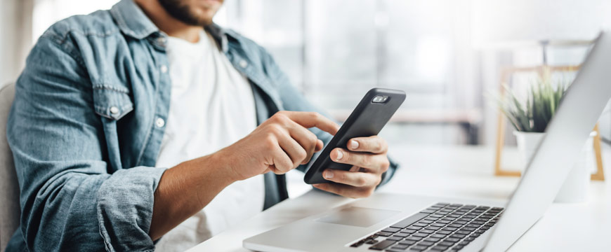 Man using cell phone and laptop